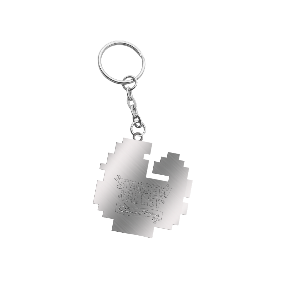 Silver metallic keychain shaped like a pixelated puzzle piece with ’stardew valley’ engraved on its surface.